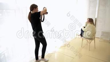 摄影师带模特坐在椅子上。 媒体。 模特被浪漫地放在靠近柔和光线窗户的椅子上